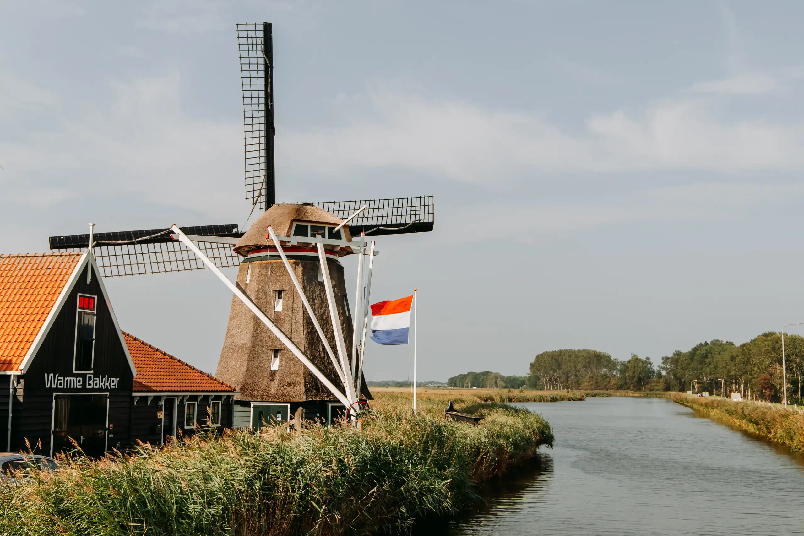 Korenmolen De Otter met nederlandse vlag en naast het kanaal